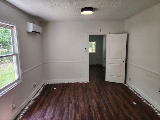 empty room with dark wood-type flooring, a textured ceiling, and a wall mounted air conditioner