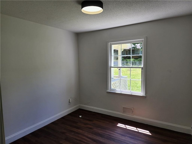 unfurnished room featuring a healthy amount of sunlight, dark hardwood / wood-style flooring, and a textured ceiling