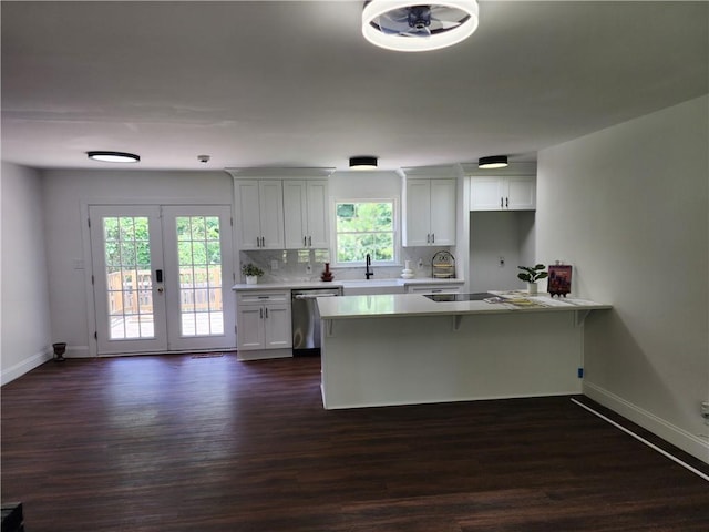 kitchen with white cabinets, stainless steel dishwasher, dark wood-type flooring, and tasteful backsplash