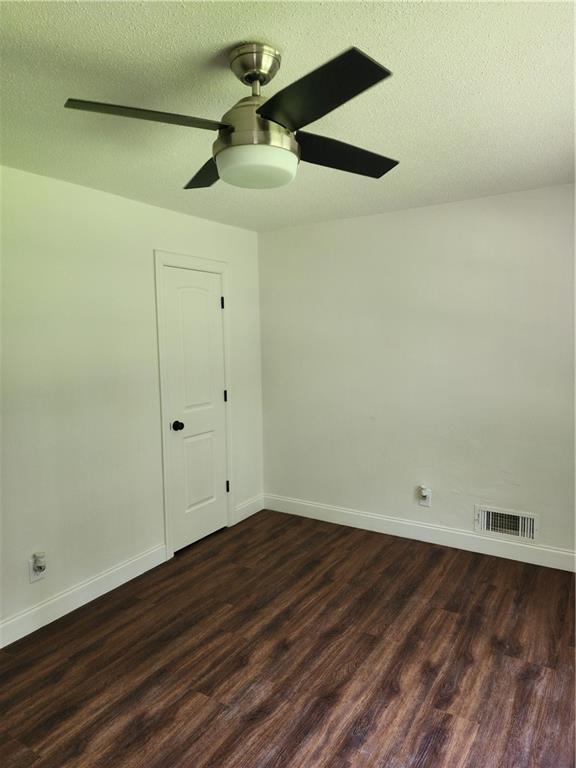 spare room featuring a textured ceiling, ceiling fan, and dark wood-type flooring