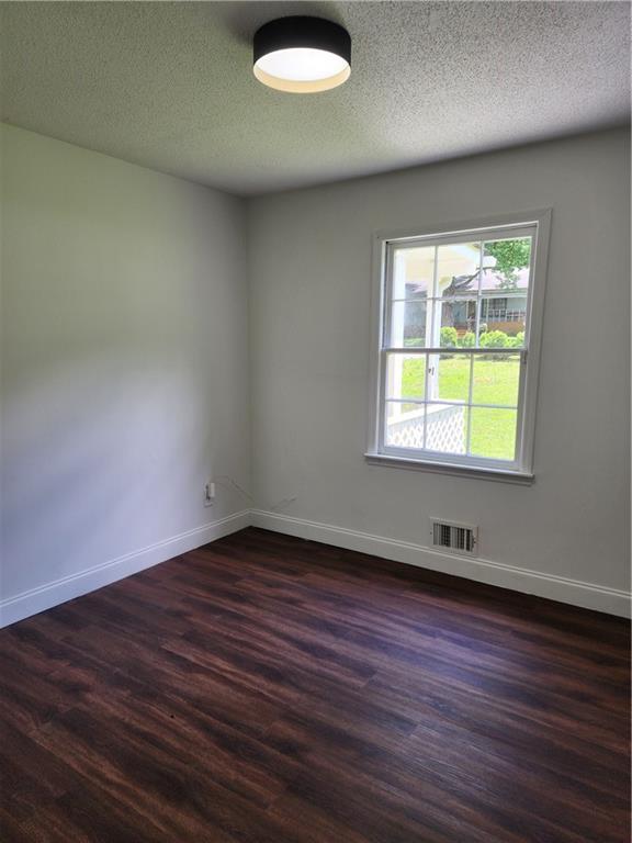 unfurnished room with a textured ceiling and dark hardwood / wood-style floors