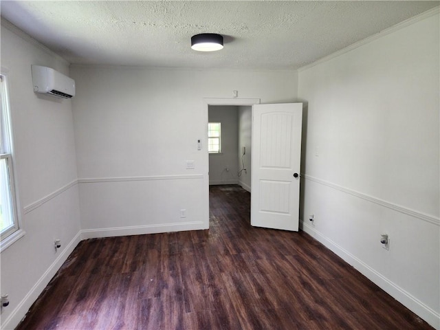 unfurnished room with a textured ceiling, a wall mounted air conditioner, and dark hardwood / wood-style floors