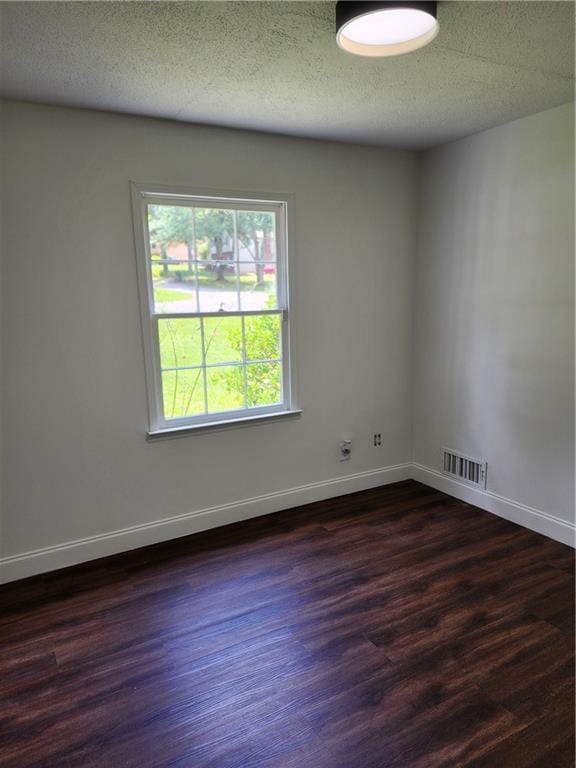 unfurnished room with a textured ceiling and dark hardwood / wood-style flooring