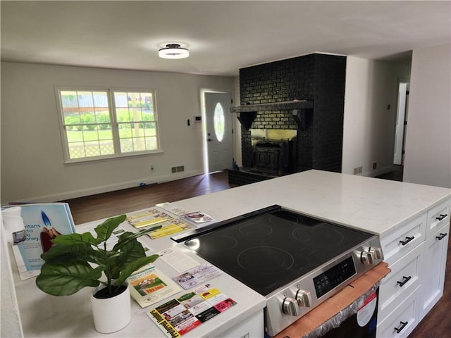 kitchen with dark hardwood / wood-style flooring, white cabinets, electric range, and a fireplace