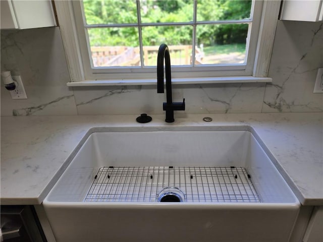 details featuring sink, white cabinetry, and tasteful backsplash