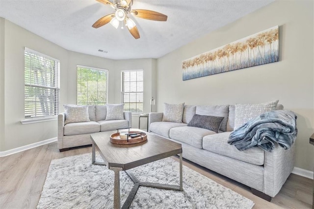 living room featuring a textured ceiling, light wood-type flooring, and ceiling fan