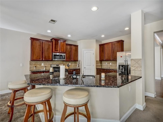 kitchen featuring a sink, tasteful backsplash, baseboards, visible vents, and appliances with stainless steel finishes