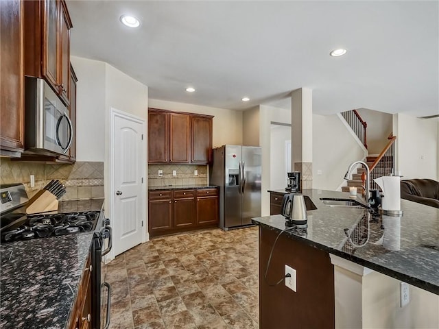 kitchen featuring recessed lighting, backsplash, a sink, dark stone counters, and appliances with stainless steel finishes