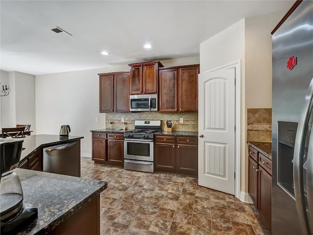 kitchen with backsplash, visible vents, appliances with stainless steel finishes, and dark stone counters