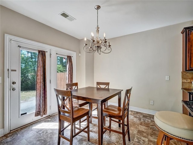 dining area with stone finish floor, visible vents, baseboards, and a notable chandelier