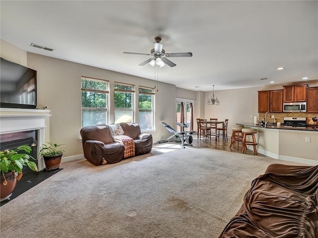 living room featuring recessed lighting, carpet floors, visible vents, and ceiling fan with notable chandelier