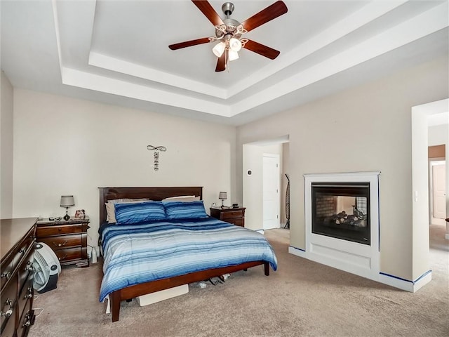 bedroom with a tray ceiling, ceiling fan, and light carpet