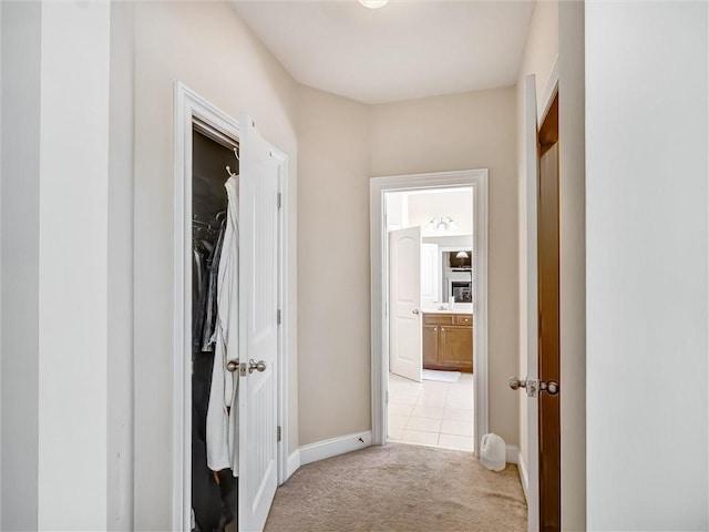 corridor with baseboards and light carpet