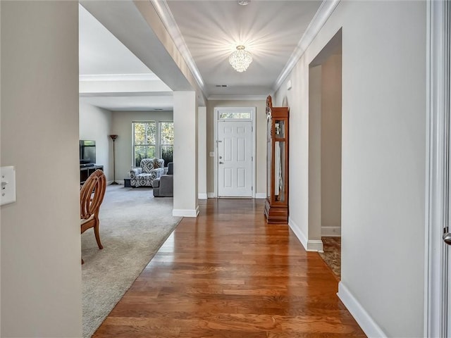 entryway featuring crown molding, wood finished floors, an inviting chandelier, baseboards, and visible vents