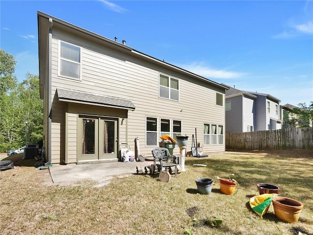 rear view of property featuring fence, a lawn, a patio area, and central AC