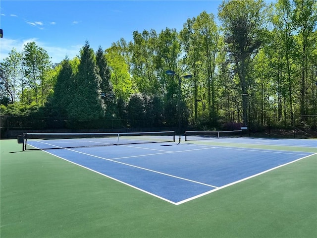 view of tennis court with community basketball court and fence