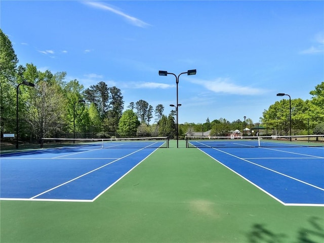 view of tennis court with community basketball court and fence