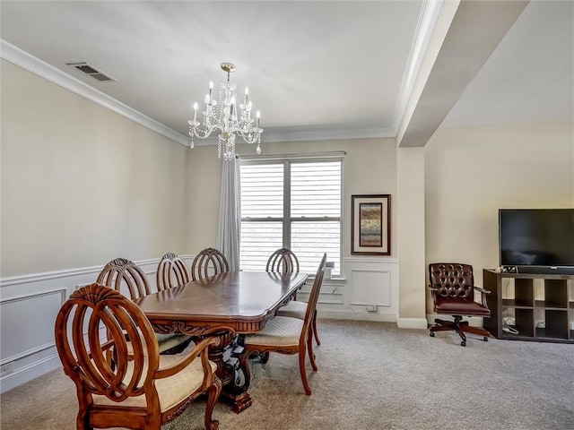 dining room with carpet, an inviting chandelier, visible vents, a decorative wall, and crown molding