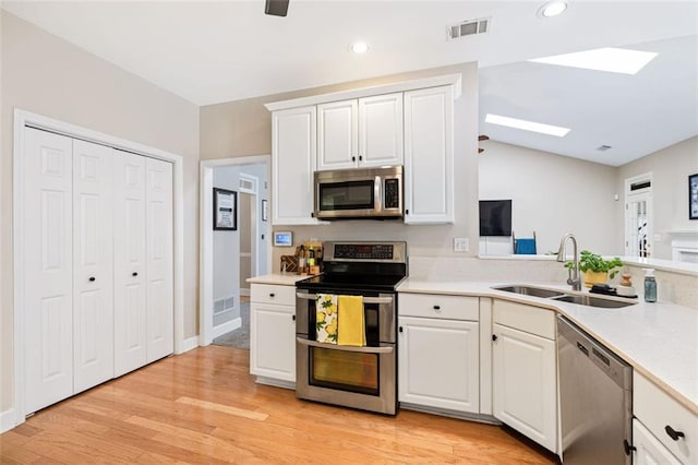 3072 Oaktree Ln, Duluth, GA 30096 - kitchen with appliances with stainless steel finishes, a skylight, light countertops, white cabinets, and lofted ceiling