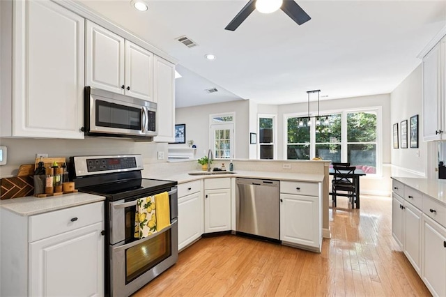 3072 Oaktree Ln, Duluth, GA 30096 - kitchen with appliances with stainless steel finishes, a peninsula, light wood-style floors, a ceiling fan, and light countertops