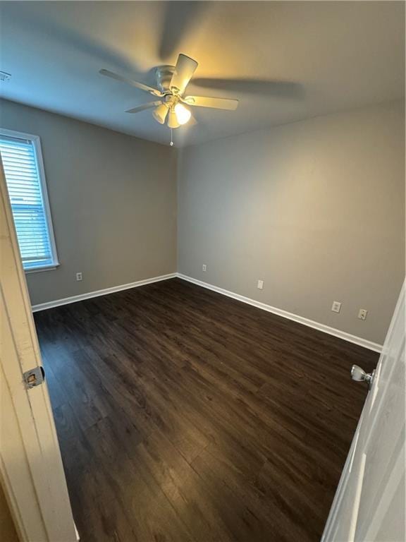 spare room featuring dark wood-style floors, visible vents, ceiling fan, and baseboards