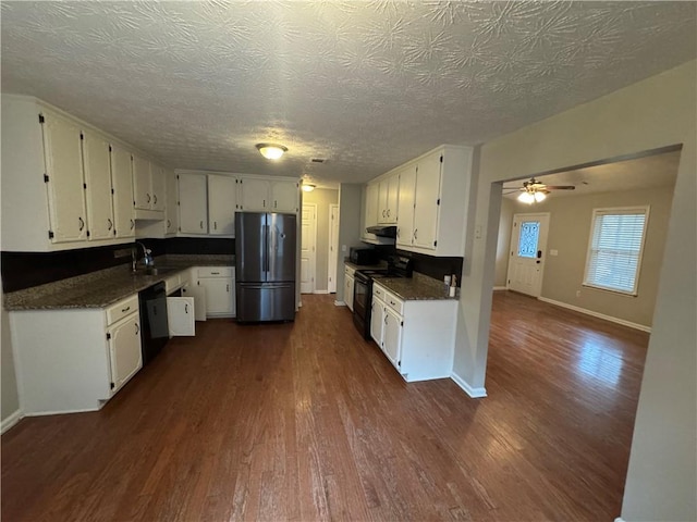 kitchen with a sink, dark countertops, black appliances, and dark wood finished floors