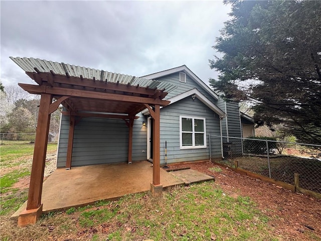 rear view of property featuring a patio area, a pergola, and fence