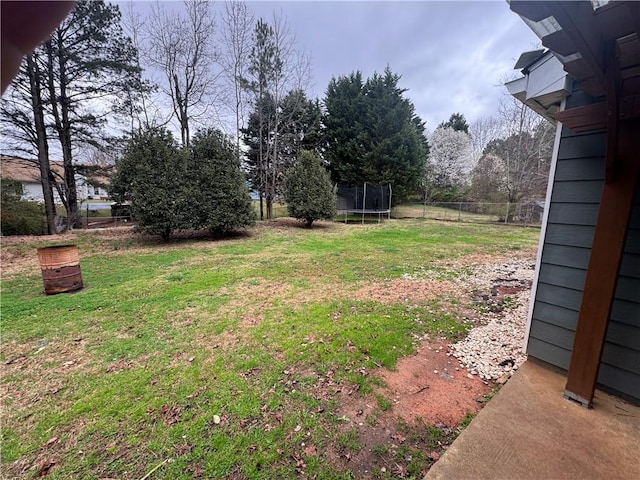 view of yard with a trampoline and fence