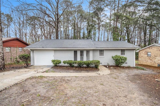 ranch-style house featuring a garage, concrete driveway, a shingled roof, crawl space, and brick siding