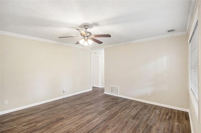 empty room featuring crown molding, dark wood-style floors, visible vents, and baseboards