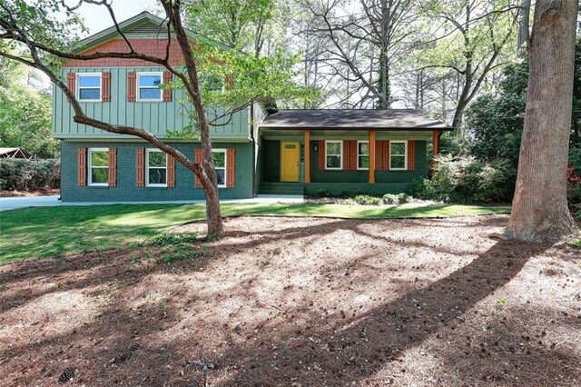 view of front of home featuring brick siding, board and batten siding, and a front lawn
