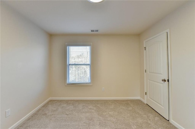 empty room with baseboards, visible vents, and light colored carpet