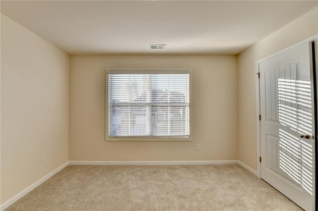 spare room featuring visible vents, light carpet, and baseboards