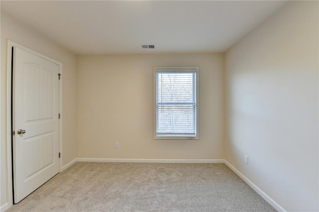 spare room featuring light carpet, visible vents, and baseboards