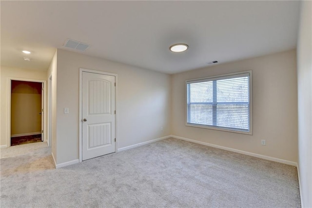 carpeted spare room featuring visible vents and baseboards