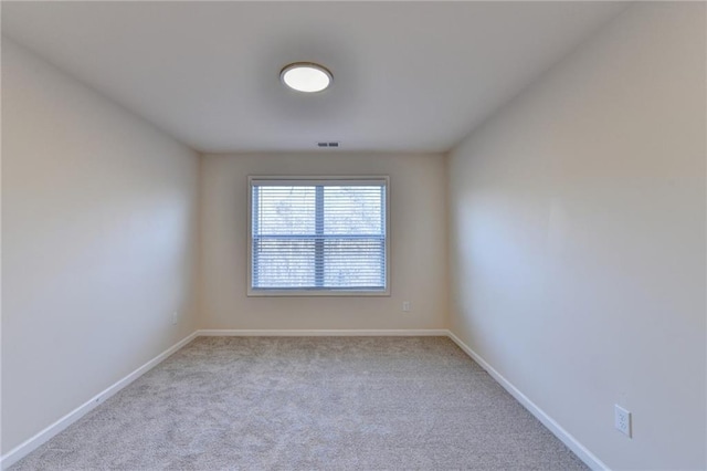 carpeted spare room featuring baseboards and visible vents