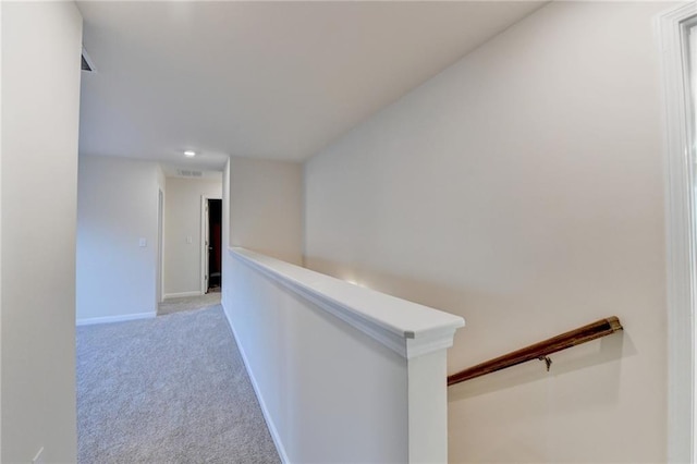 hallway featuring baseboards, light colored carpet, visible vents, and an upstairs landing