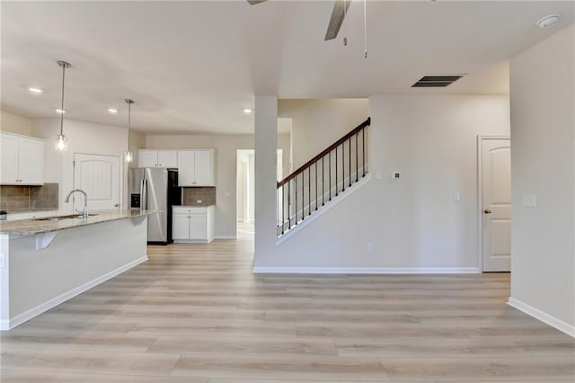 kitchen with light wood-style floors, white cabinetry, a sink, and stainless steel fridge with ice dispenser