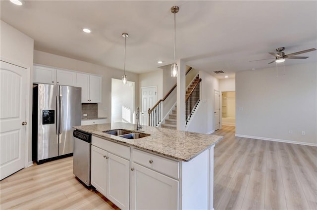 kitchen with light wood-style flooring, stainless steel appliances, white cabinetry, pendant lighting, and a sink