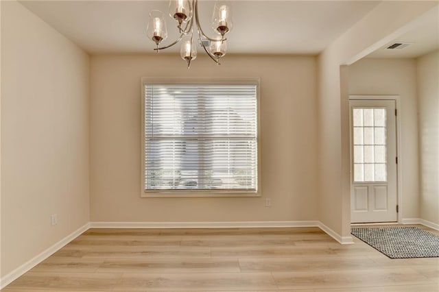 unfurnished dining area featuring a notable chandelier, baseboards, visible vents, and light wood-style floors