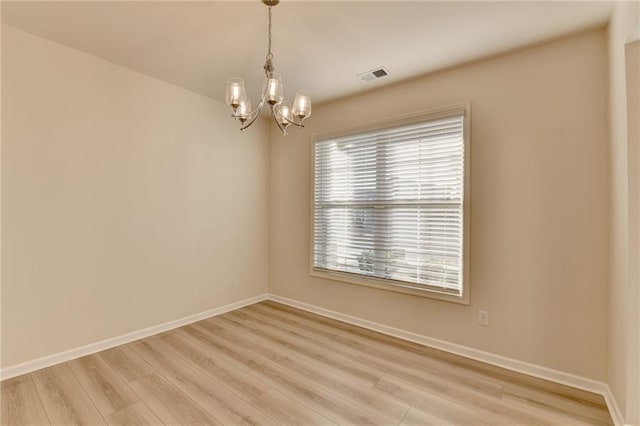 empty room featuring baseboards, an inviting chandelier, visible vents, and light wood-style floors