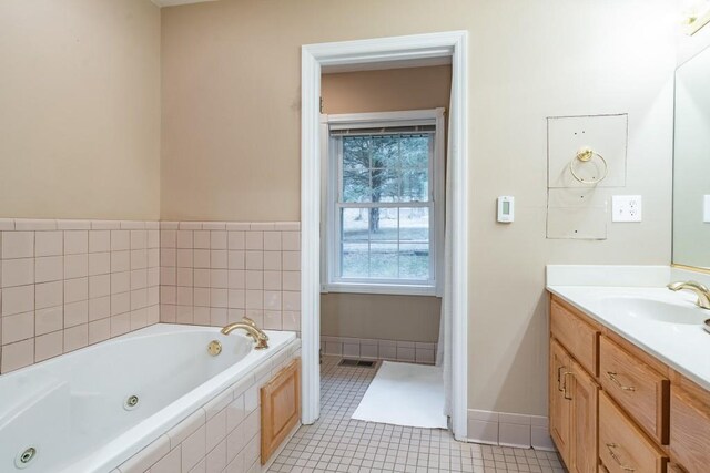 bathroom featuring tile patterned floors, vanity, and tiled bath