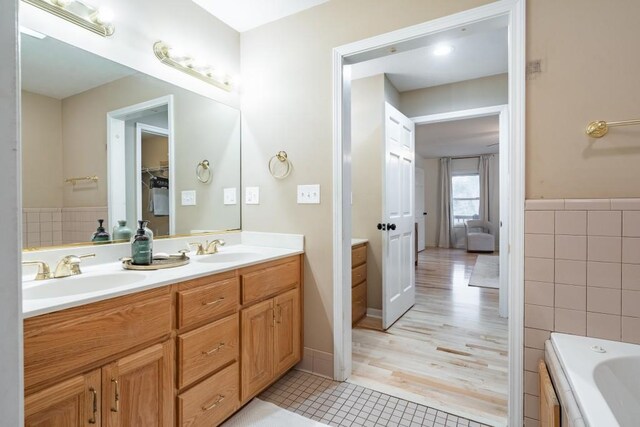 bathroom with vanity, tile patterned floors, tile walls, and a tub