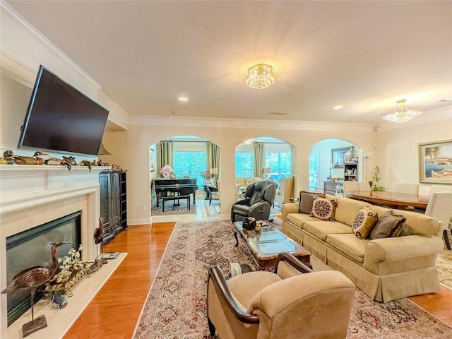 6416 Hickory Springs Cir, Hoschton, GA 30548 - living area with a chandelier, crown molding, arched walkways, a glass covered fireplace, and light wood-style floors