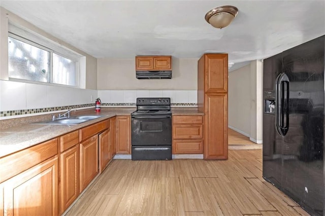 kitchen featuring sink, light wood-type flooring, ventilation hood, black appliances, and decorative backsplash