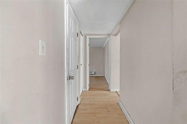 hallway with light hardwood / wood-style floors and baseboard heating