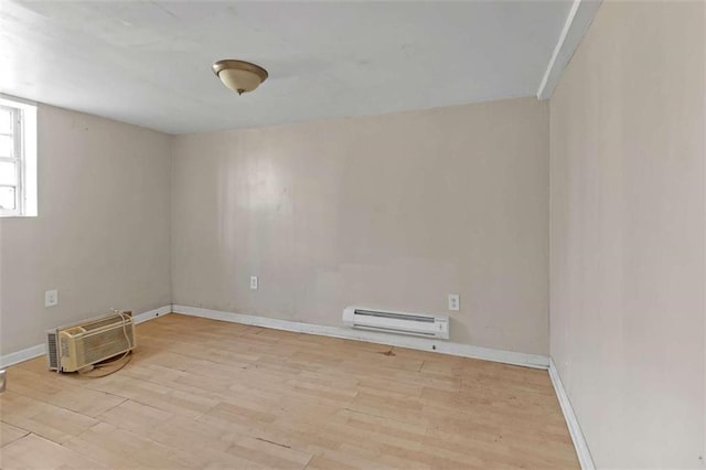 unfurnished room featuring baseboard heating, light hardwood / wood-style flooring, and a wall mounted air conditioner