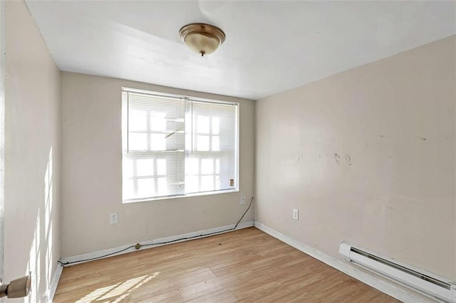 spare room featuring light wood-type flooring and a baseboard heating unit