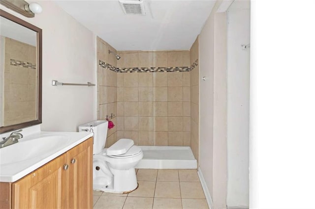 bathroom with tile patterned floors, vanity, a tile shower, and toilet