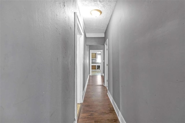 corridor featuring a textured ceiling and dark hardwood / wood-style flooring